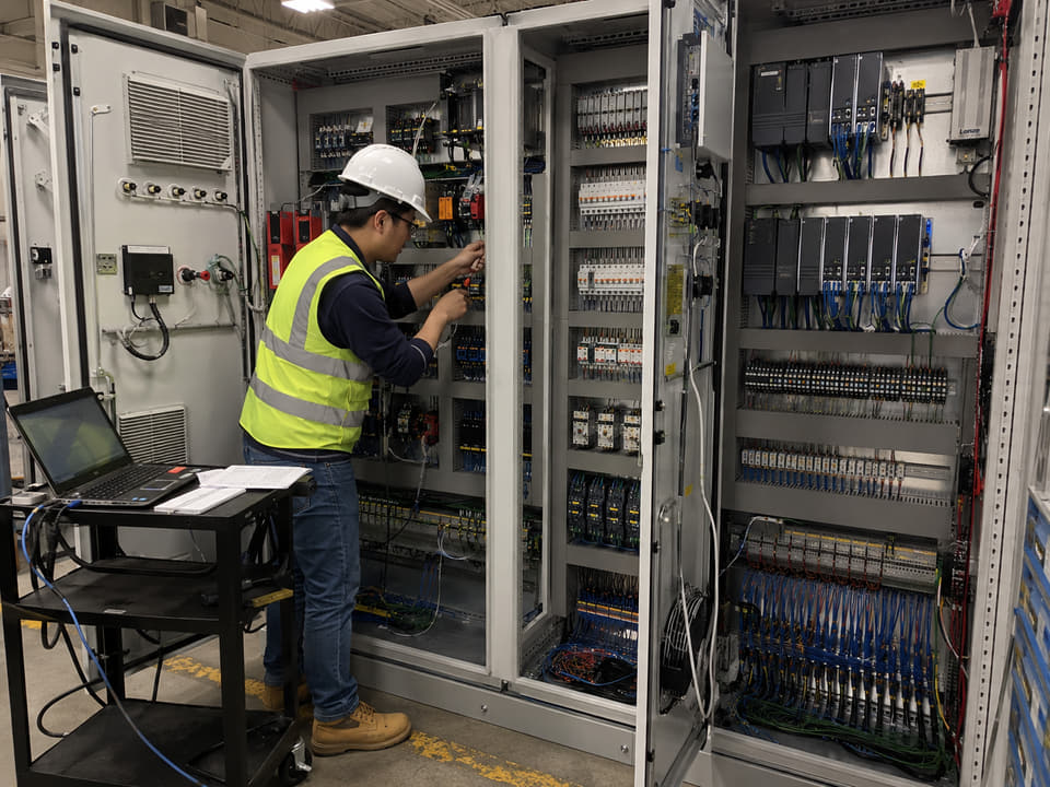 Engineer troubleshooting a multi-bay controls cabinet during commissioning.