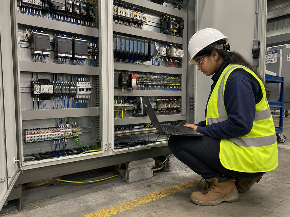 Engineer validating controls hardware with laptop during field support.